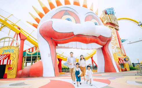 Family enjoying a day at Ocean Park with colorful roller coaster and clown entrance.
