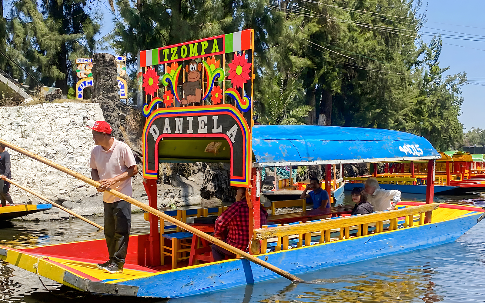 Trajinera boat with passengers on Xochimilco canal, Mexico City.