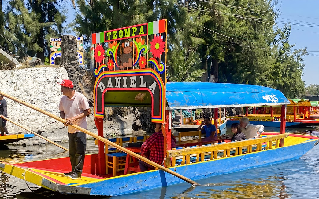 Trajinera boat with passengers on Xochimilco canal, Mexico City.