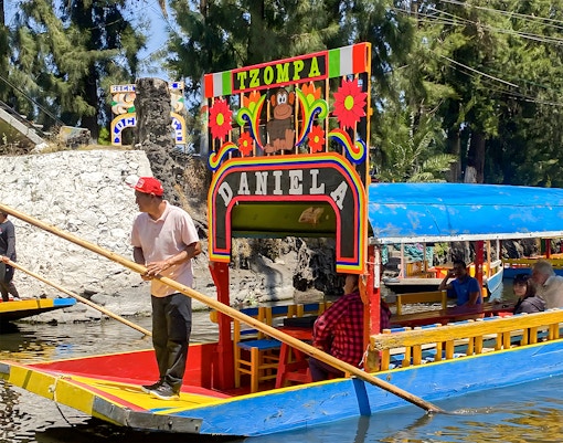 Trajinera boat with passengers on Xochimilco canal, Mexico City.