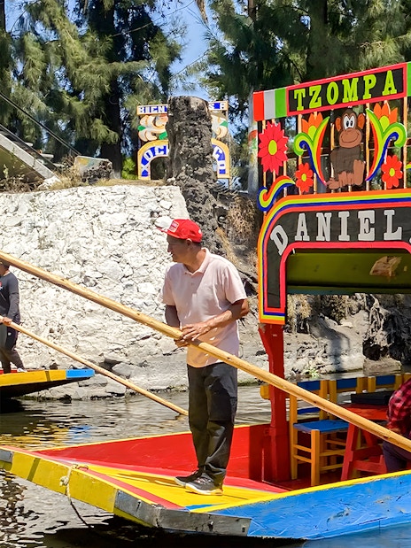Trajinera boat with passengers on Xochimilco canal, Mexico City.