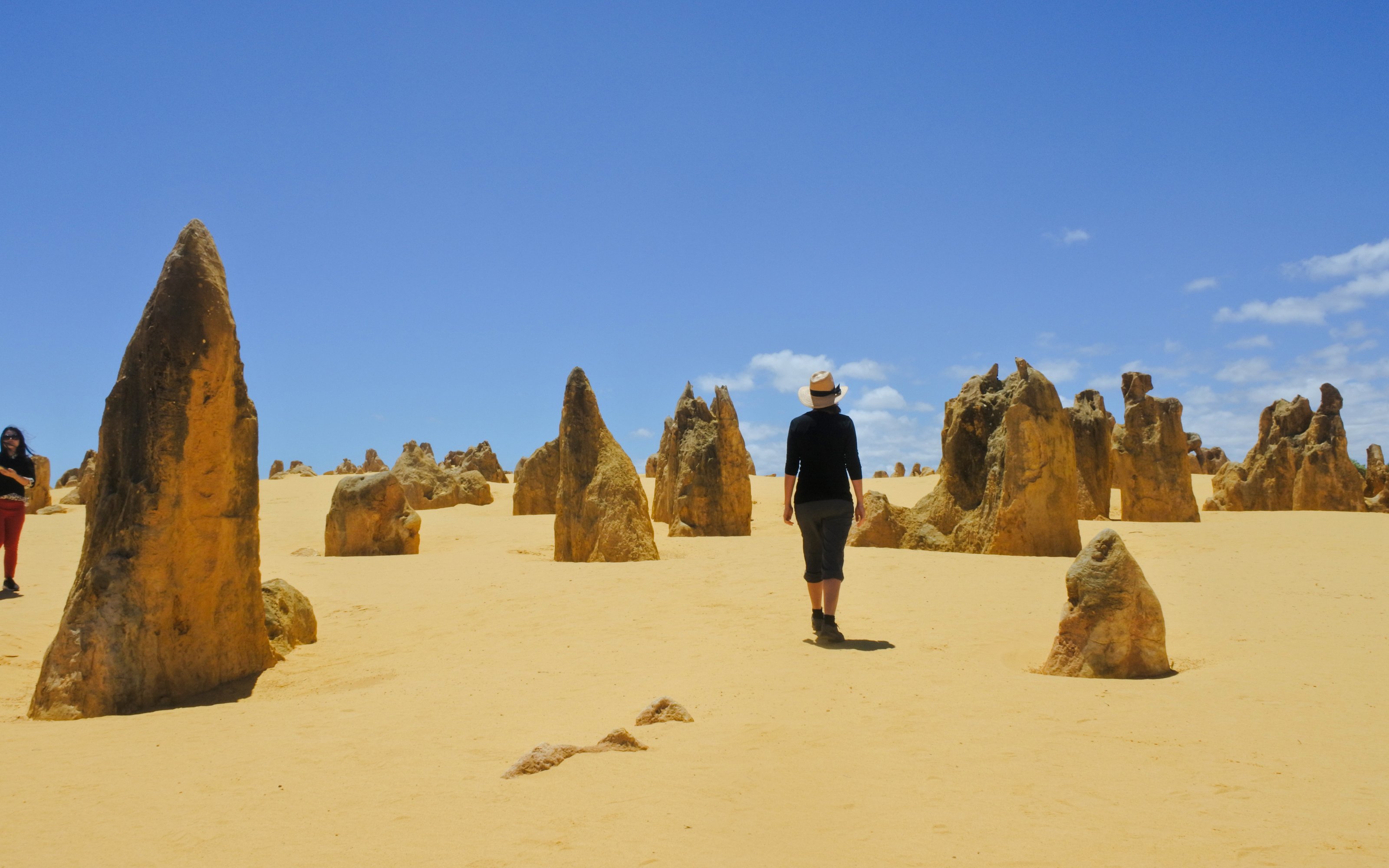 Woman hiking among limestone formations at Pinnacles Desert, Western Australia.