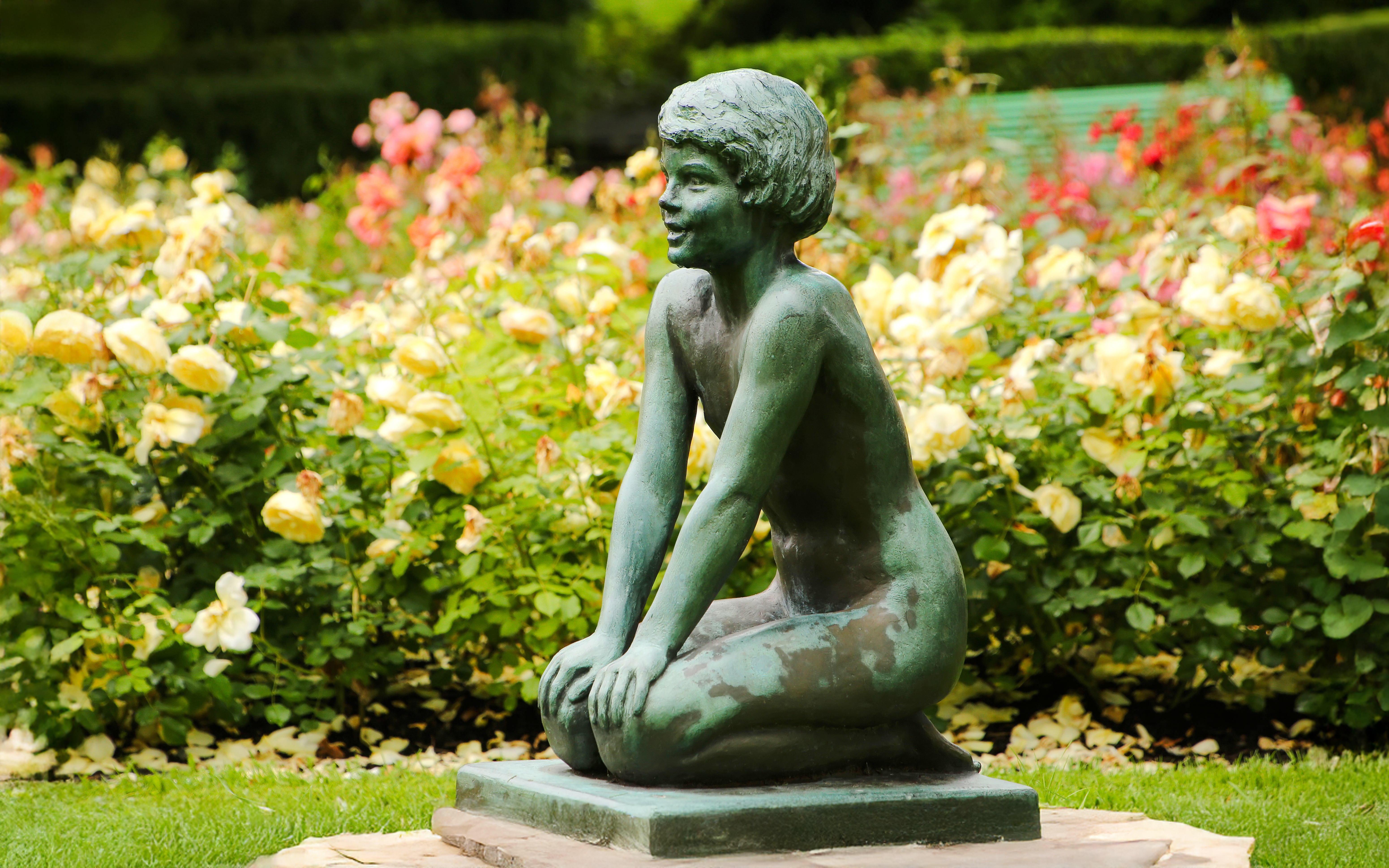 Kneeling girl statue surrounded by flowers in Byparken, Haugesund.