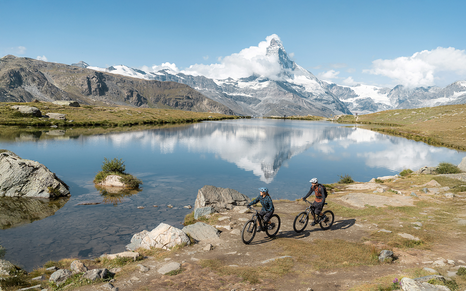 Tourists cycling near Stellisee river with Matterhorn in Zermatt, Switzerland.