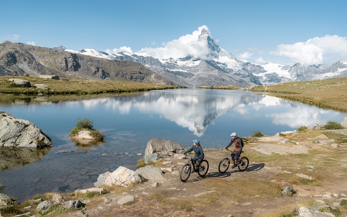 Tourists cycling near Stellisee river with Matterhorn in Zermatt, Switzerland.