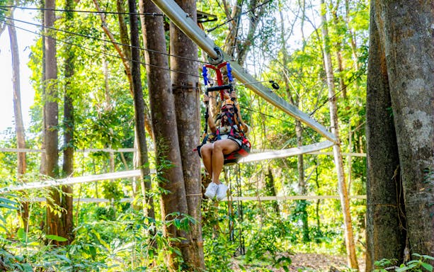 Person ziplining through forest on Sky Rock Roller Adventure in Khao Lak.