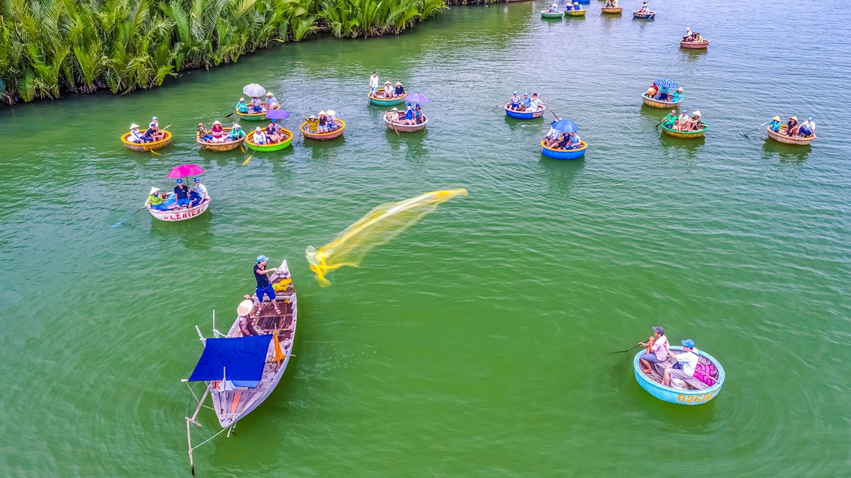 Aerial view of Hoi An fishing net activity with round boats on green water.