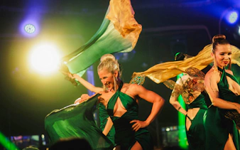 Performers at Burlesque Dinner Club, Vienna, dancing with green and gold fabric under stage lights.