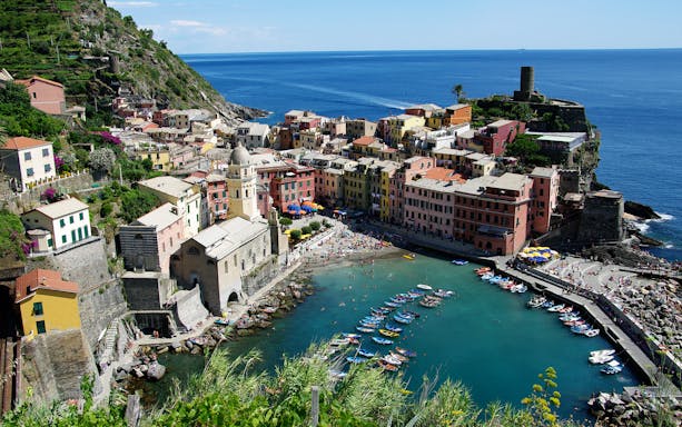 Vernazza village and harbor in Cinque Terre, Italy, viewed from above with colorful buildings and boats.