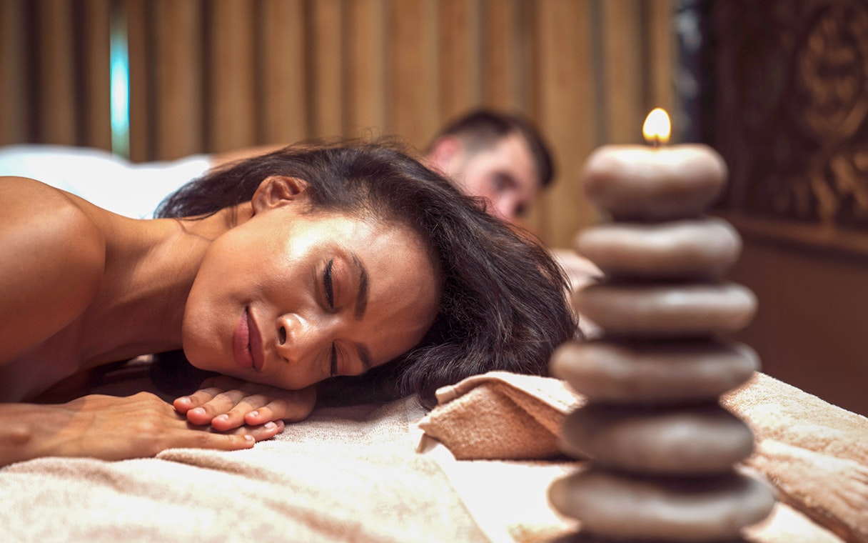 Guest relaxing at Istanbul private Turkish bath with stacked stones and candle.