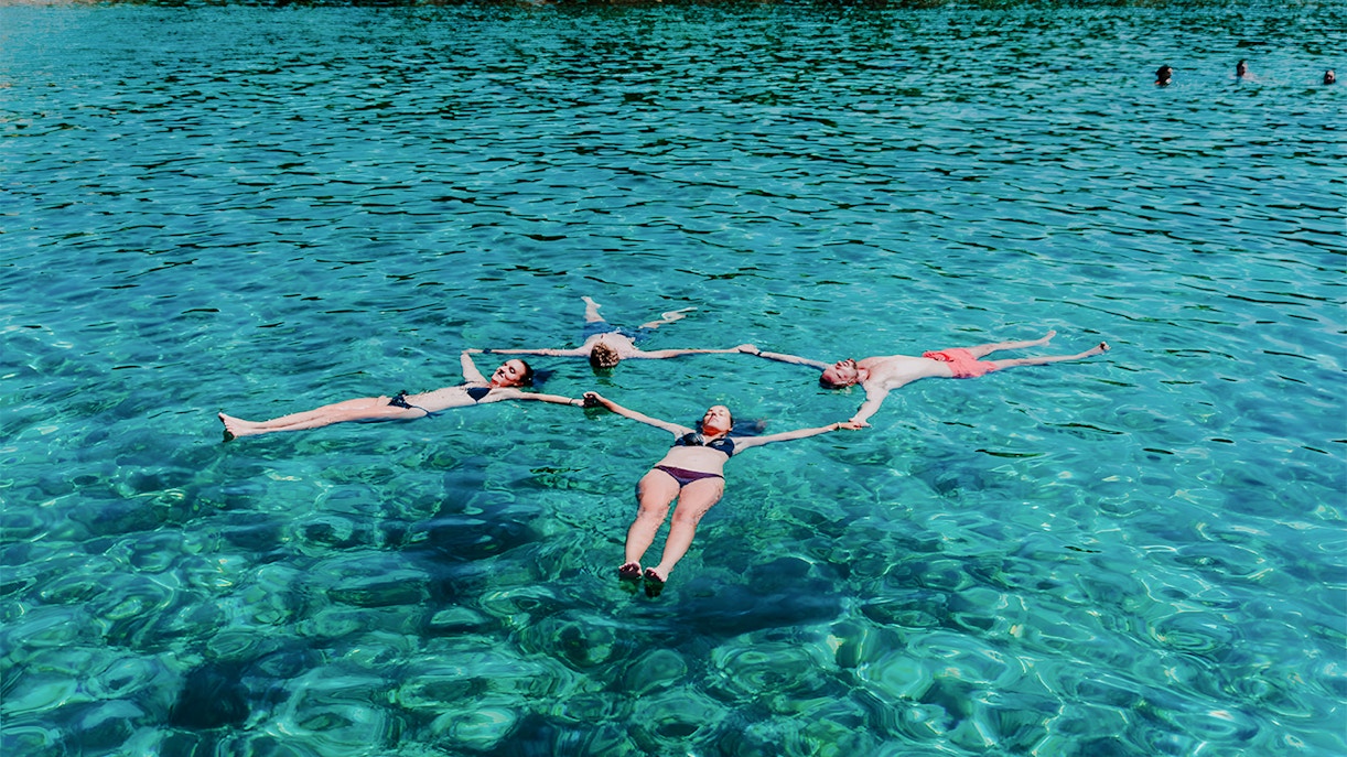 Group swimming in clear waters on Blue Cave, Blue Lagoon & 5 Islands tour.