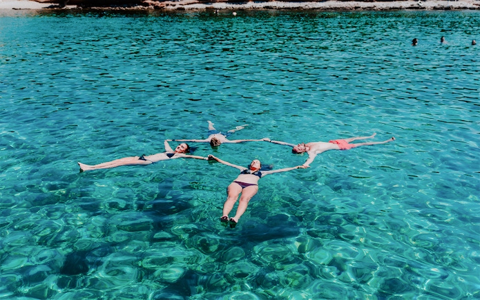Group swimming in clear waters on Blue Cave, Blue Lagoon & 5 Islands tour.