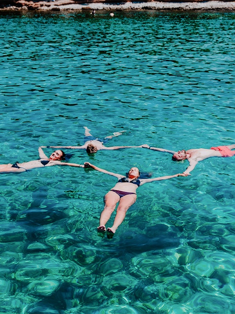 Group swimming in clear waters on Blue Cave, Blue Lagoon & 5 Islands tour.