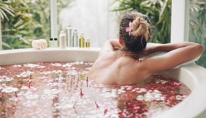 Woman enjoying outside view while spa bathing with flowers