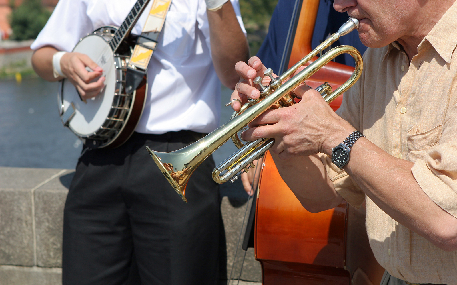 Street musicians playing trumpet and banjo by a river in Prague.