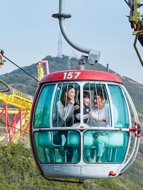 Cable car ride at Ocean Park with family enjoying views of amusement rides and mountains.