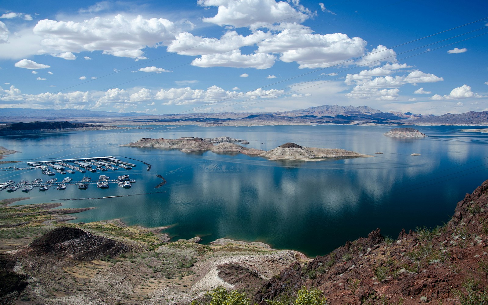 Marina and islands on Lake Mead with distant mountains under a cloudy sky.