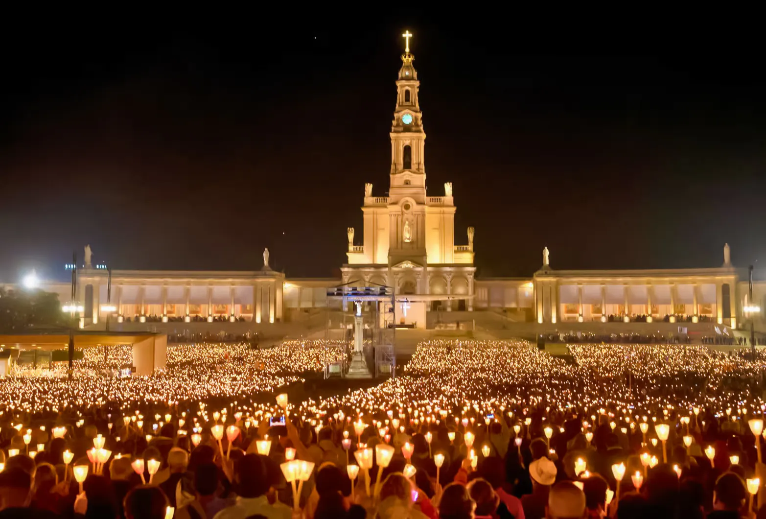 Candlelight procession at Fátima Sanctuary, Portugal, with a large crowd holding candles at night.