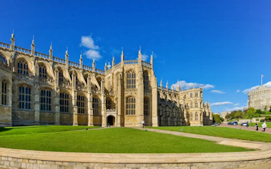 St George’s Chapel exterior with blue sky and green lawn, Windsor Castle in background.