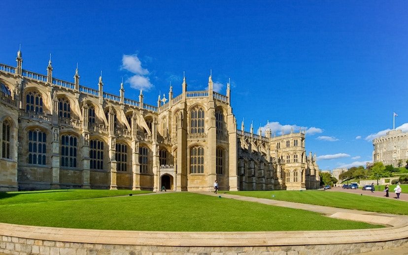 St George’s Chapel exterior with blue sky and green lawn, Windsor Castle in background.