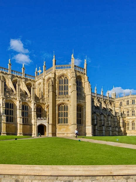 St George’s Chapel exterior with blue sky and green lawn, Windsor Castle in background.