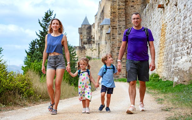 Family walking near Carcassonne castle on guided tour.