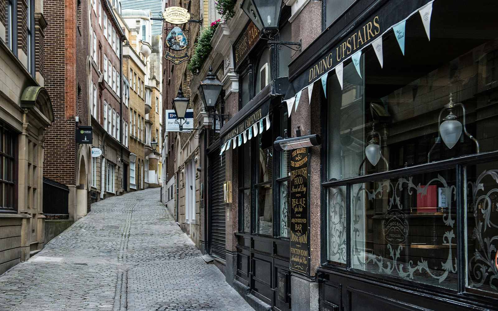 Narrow cobblestone street in London resembling Diagon Alley from Harry Potter.