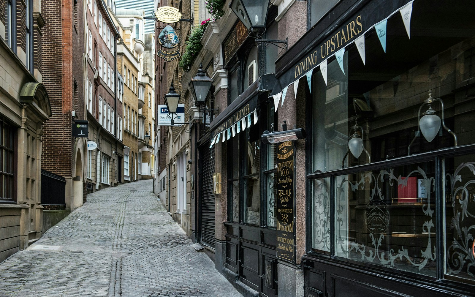 Narrow cobblestone street in London resembling Diagon Alley from Harry Potter.