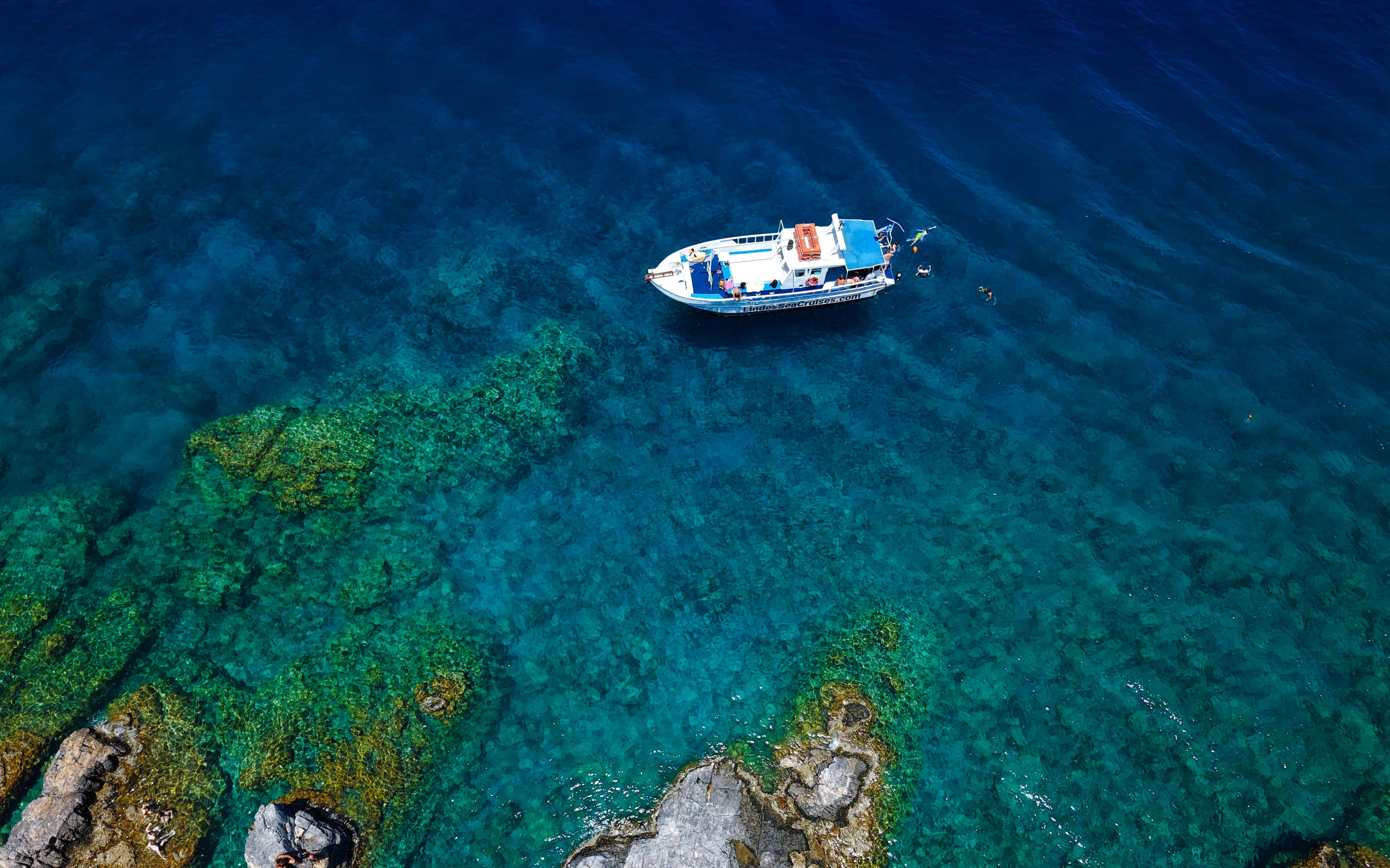 Boat on turquoise sea during Lindos Sunset Cruise, Greece.