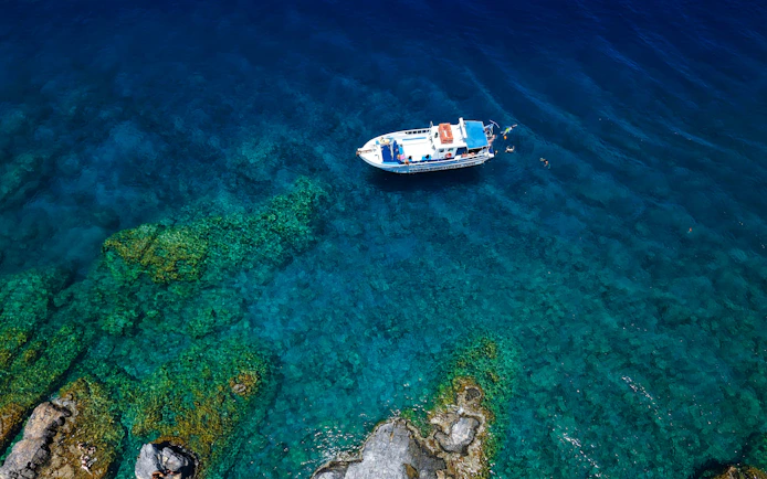 Boat on turquoise sea during Lindos Sunset Cruise, Greece.