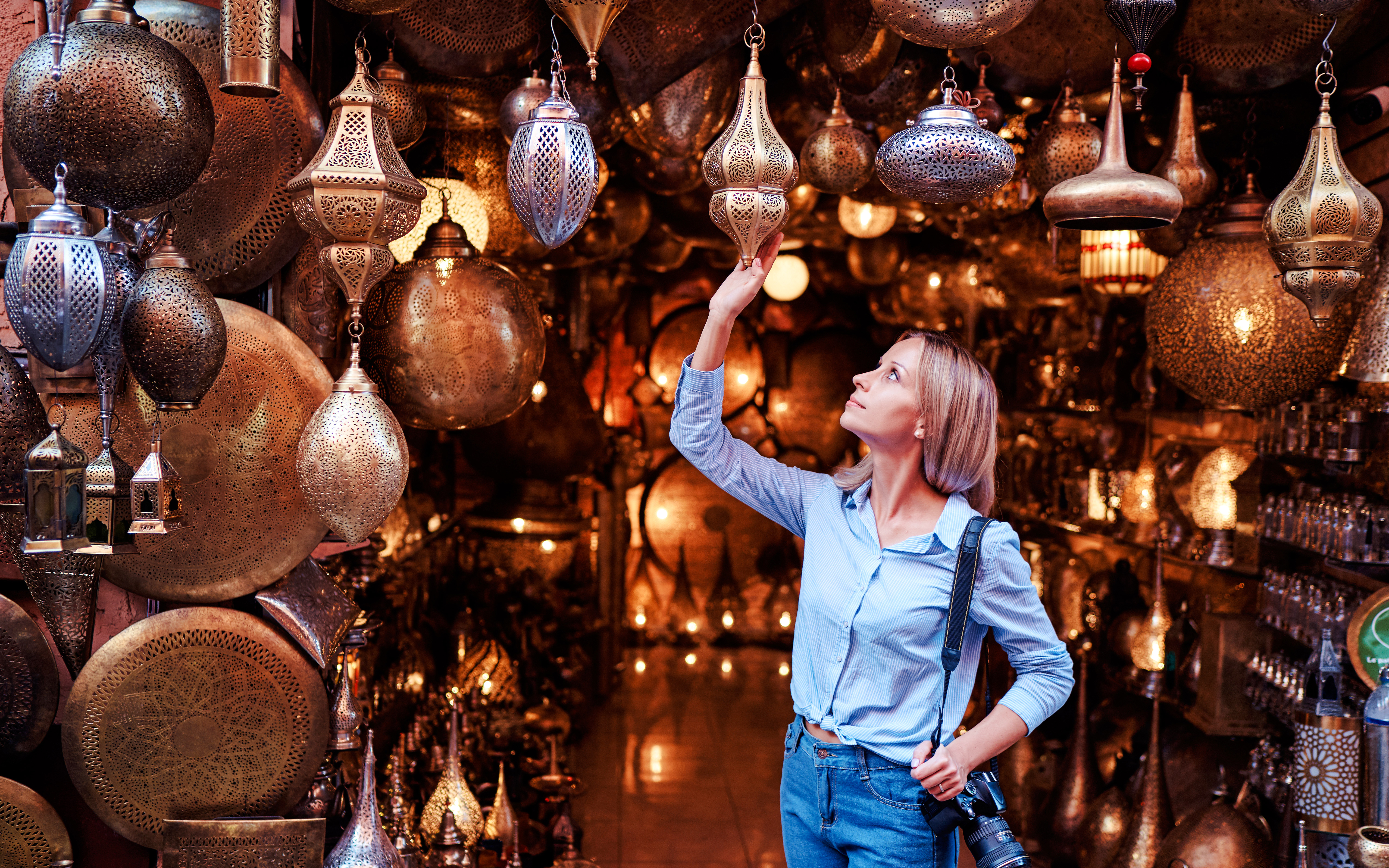 Young woman selecting copper lanterns in Casablanca souvenir shop, Morocco.