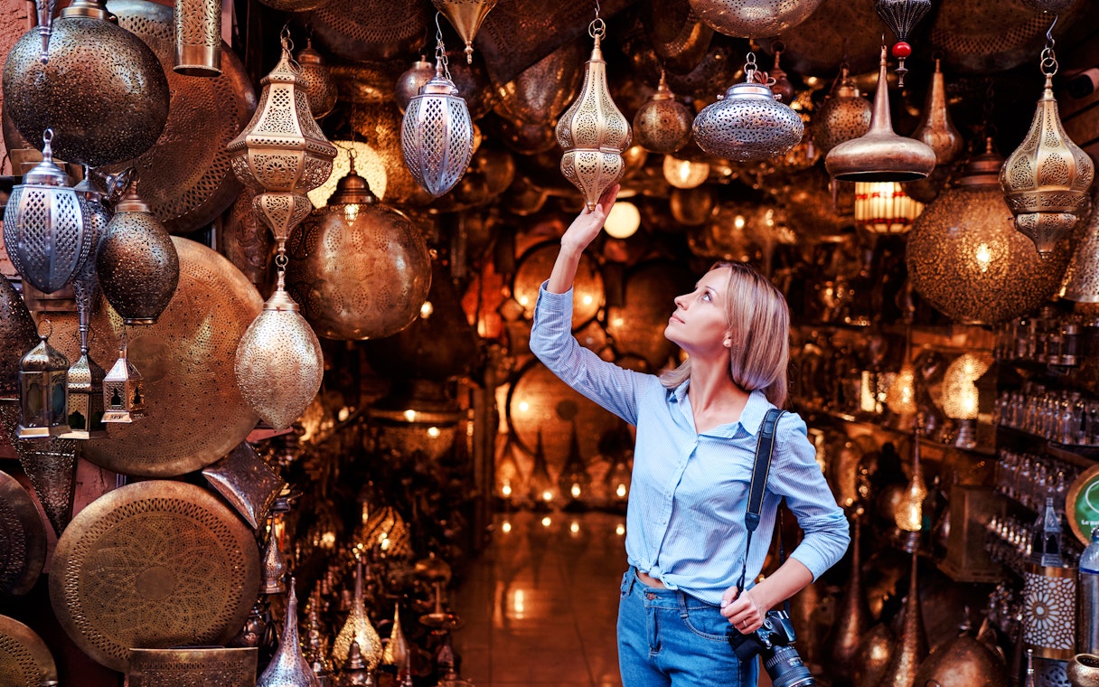 Young woman selecting copper lanterns in Casablanca souvenir shop, Morocco.