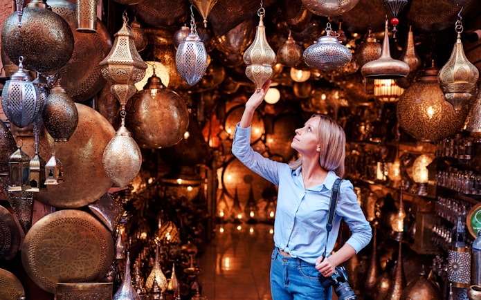 Young woman selecting copper lanterns in Casablanca souvenir shop, Morocco.