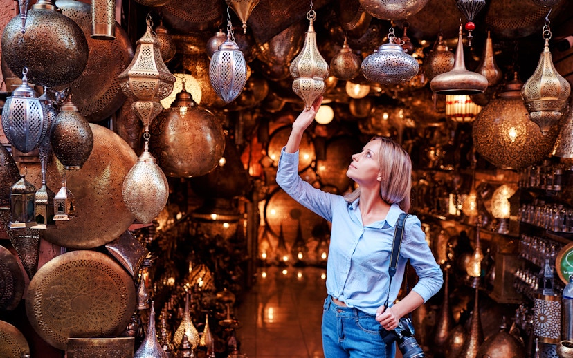 Young woman selecting copper lanterns in Casablanca souvenir shop, Morocco.