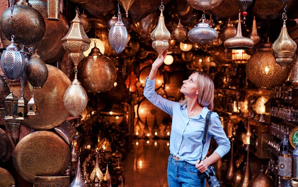 Young woman selecting copper lanterns in Casablanca souvenir shop, Morocco.