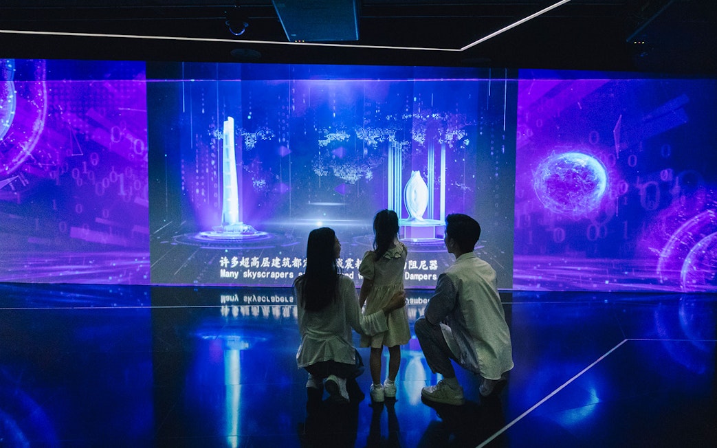 Family exploring digital skyscraper exhibit inside Shanghai Tower.
