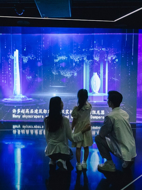Family exploring digital skyscraper exhibit inside Shanghai Tower.
