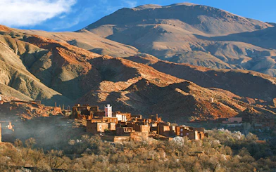Traditional Berber village in Ourika Valley with Atlas Mountains backdrop.