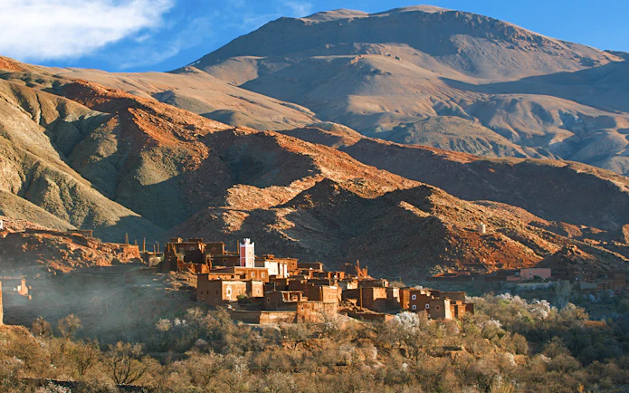 Traditional Berber village in Ourika Valley with Atlas Mountains backdrop.
