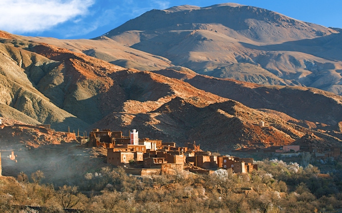 Traditional Berber village in Ourika Valley with Atlas Mountains backdrop.