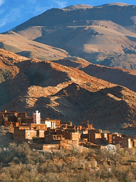 Traditional Berber village in Ourika Valley with Atlas Mountains backdrop.