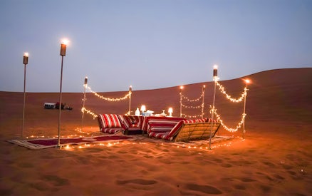 Desert dining setup with cushions and lights for Dubai private luxury family dinner.