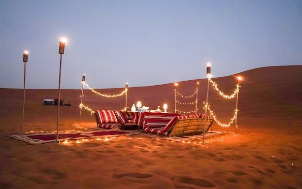 Desert dining setup with cushions and lights for Dubai private luxury family dinner.