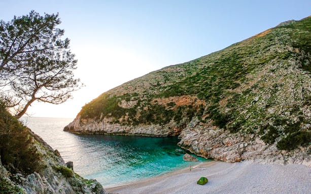 Secluded beach with turquoise waters and rocky cliffs on the Blue Caves Albania tour.