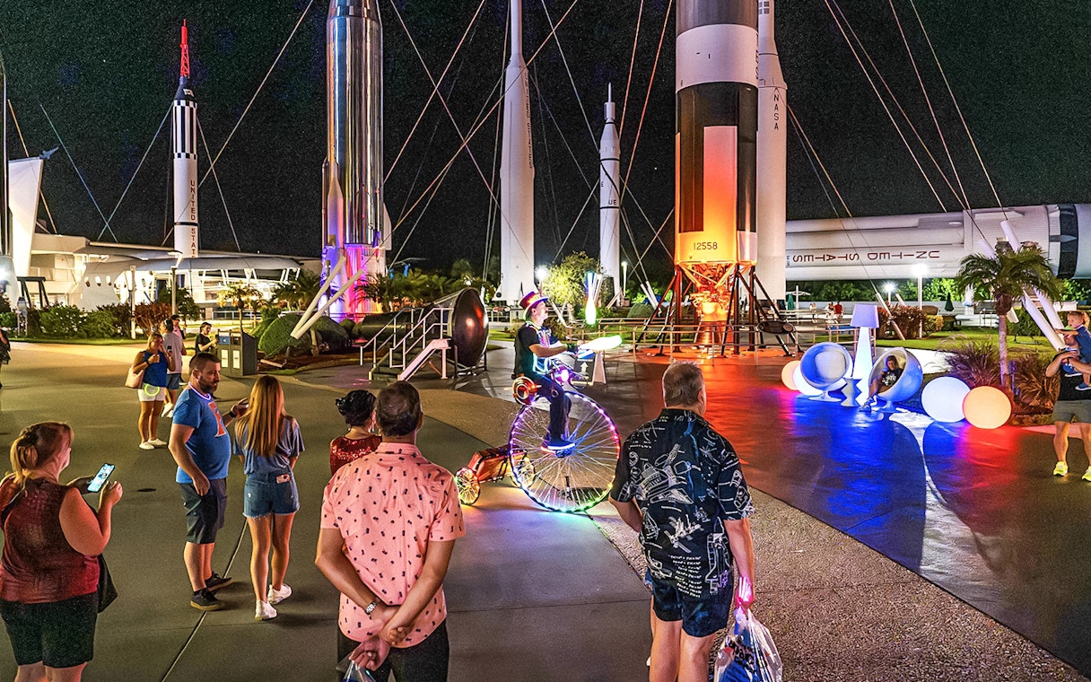 Guests exploring illuminated rockets at Kennedy Space Center after-hours event.