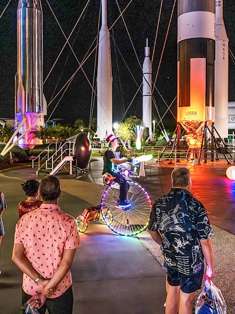Guests exploring illuminated rockets at Kennedy Space Center after-hours event.
