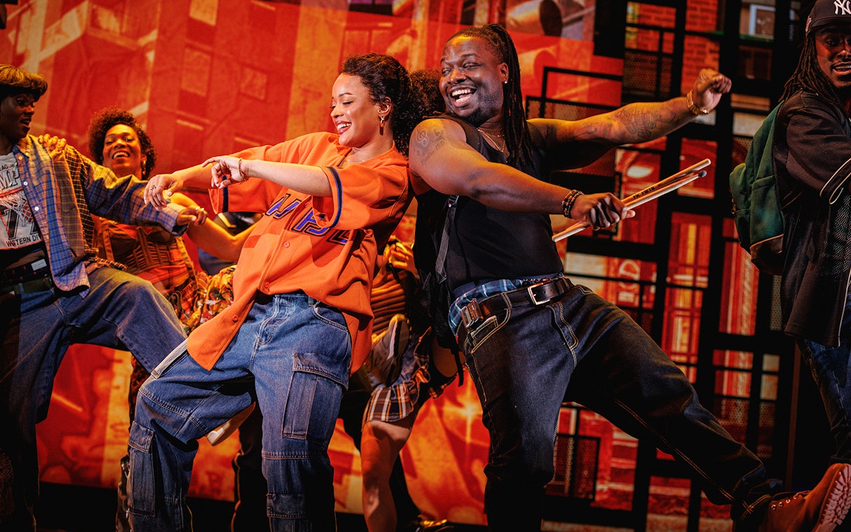 Performers dancing energetically on stage in Hell's Kitchen show.