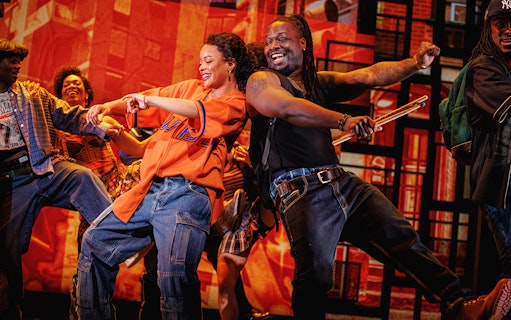 Performers dancing energetically on stage in Hell's Kitchen show.