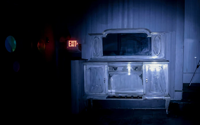 Antique dresser in dimly lit room with exit sign, Savannah paranormal tour.
