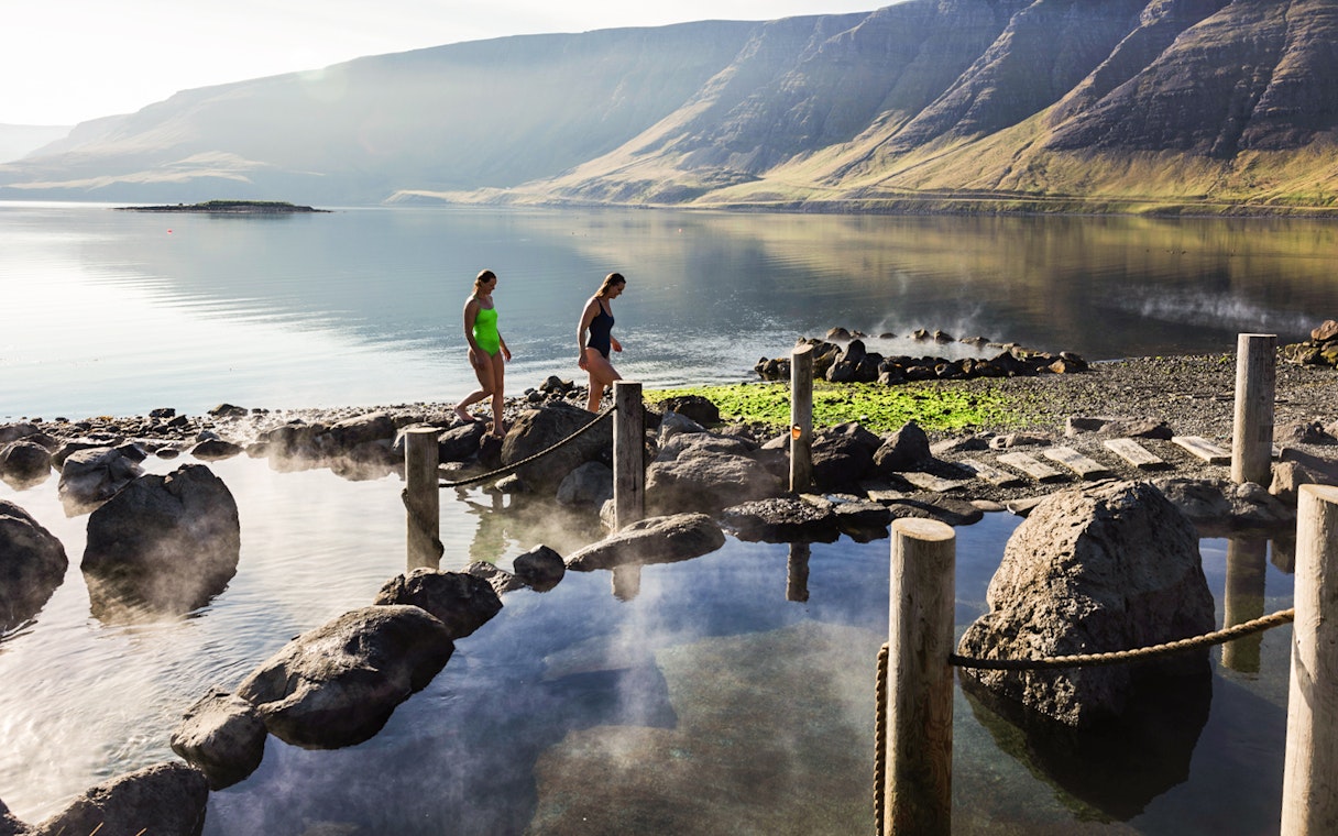 Visitors enjoying Hvammsvík Hot Spring with scenic mountain views near Reykjavík.